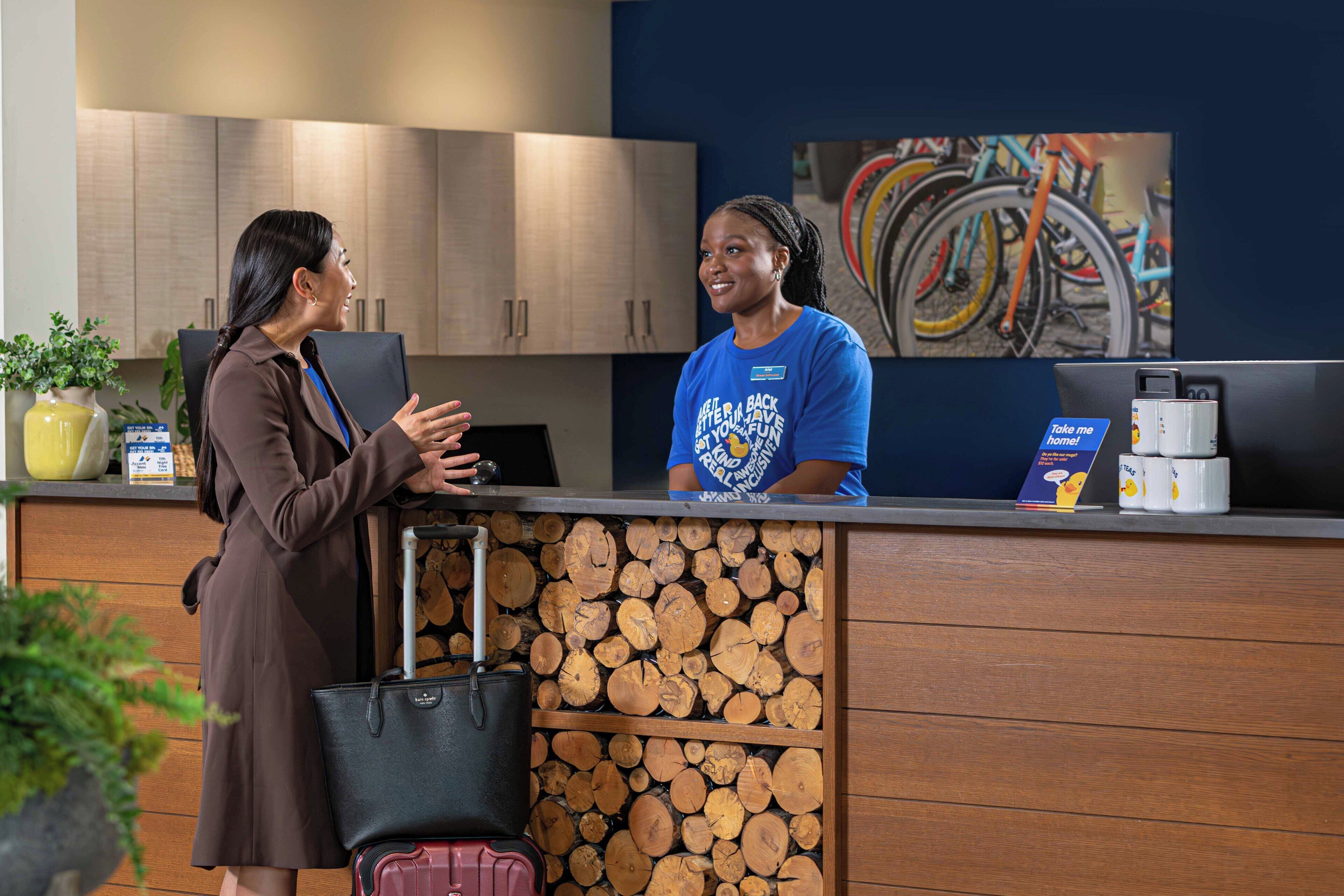 A reception desk with a wooden log display, a laptop, and a coffee machine.