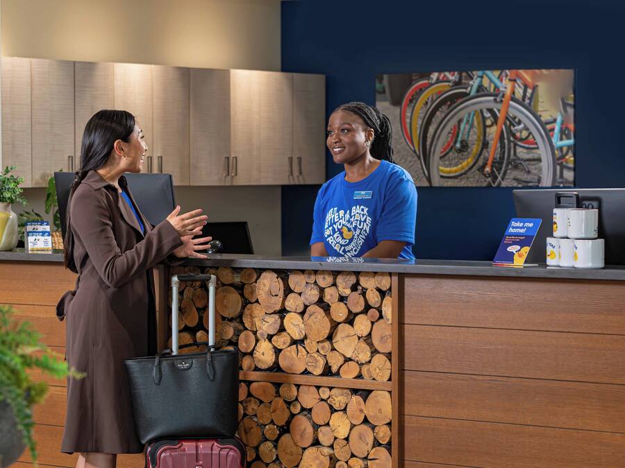 A reception desk with a wooden log display, a laptop, and a coffee machine.