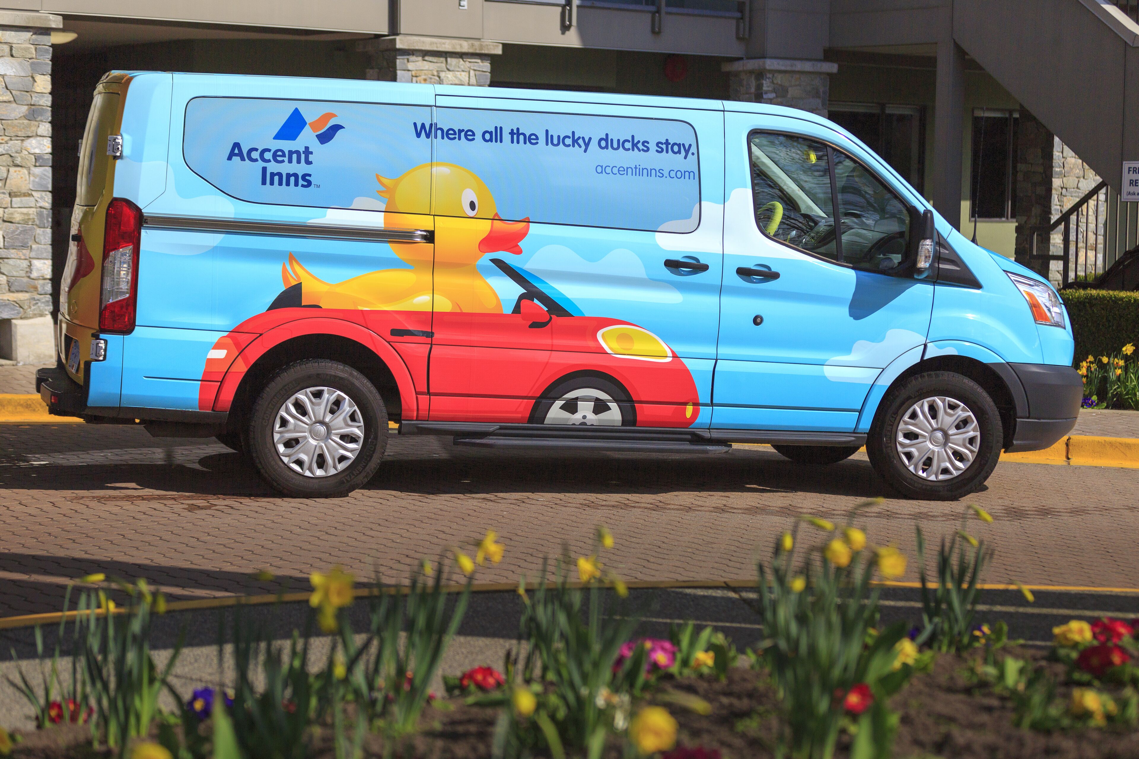 A blue van with a duck and car graphic, advertising Accent Inns.