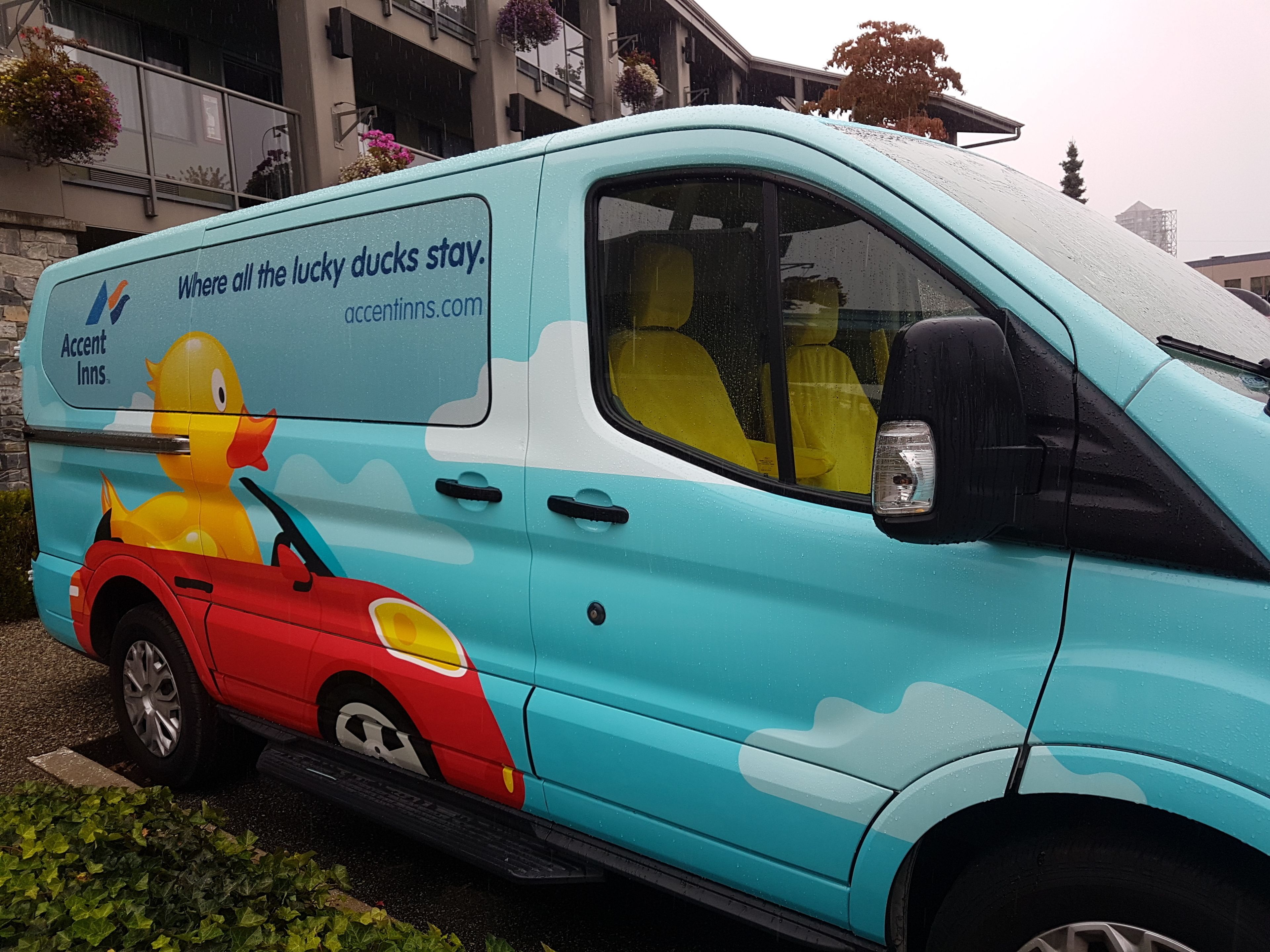 A light blue van with a duck illustration and text advertising Accent Inns.