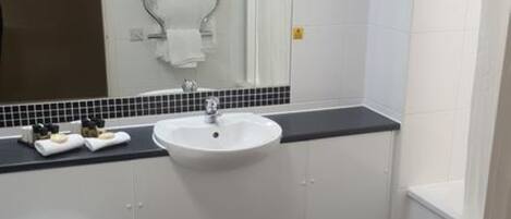 A bathroom with a white toilet, a sink with a black countertop, and a mirror above the sink.