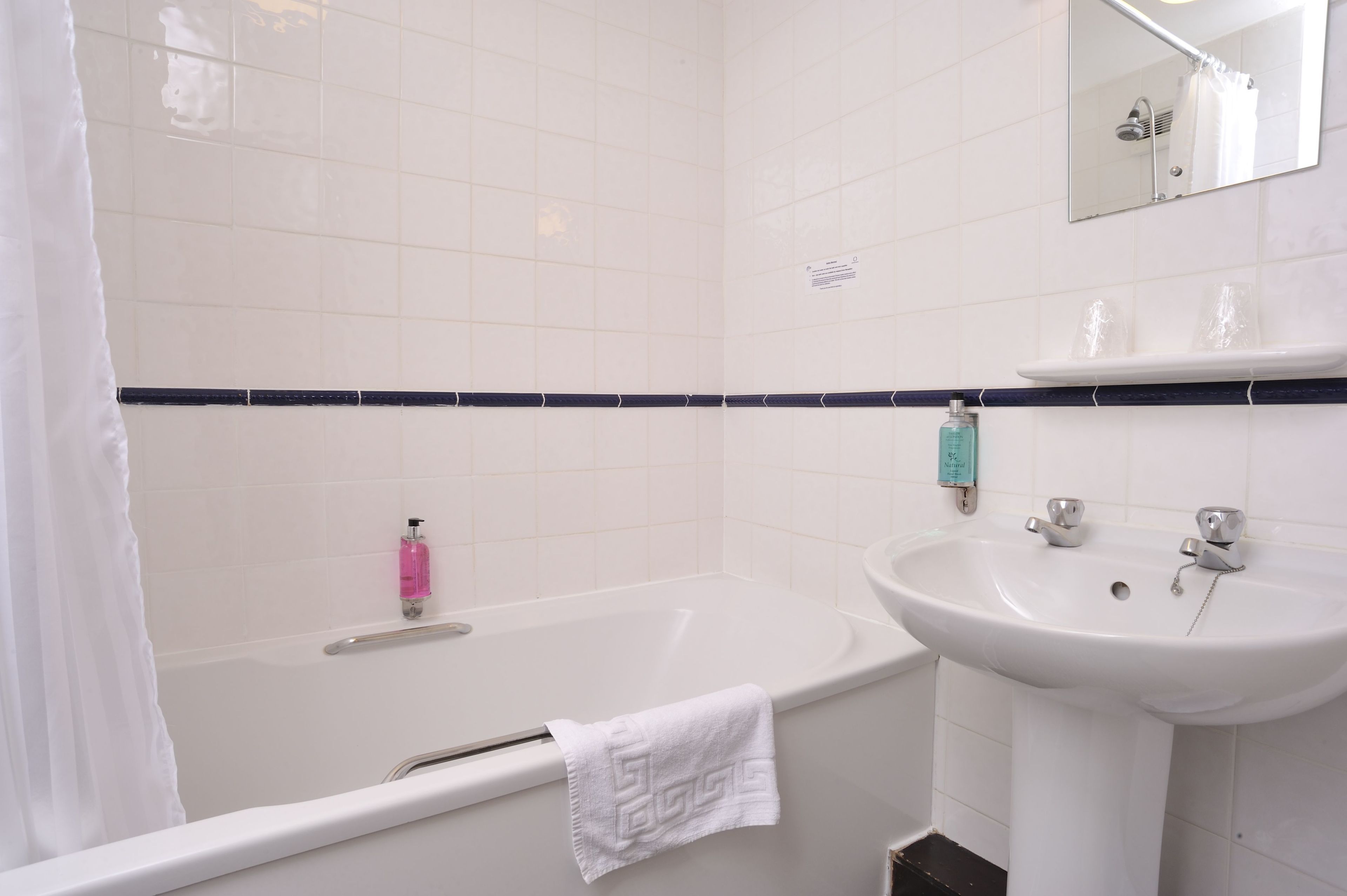A bathroom with a bathtub, a sink, and a mirror.