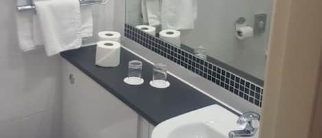 Un baño con inodoro, lavamanos y toalleros.