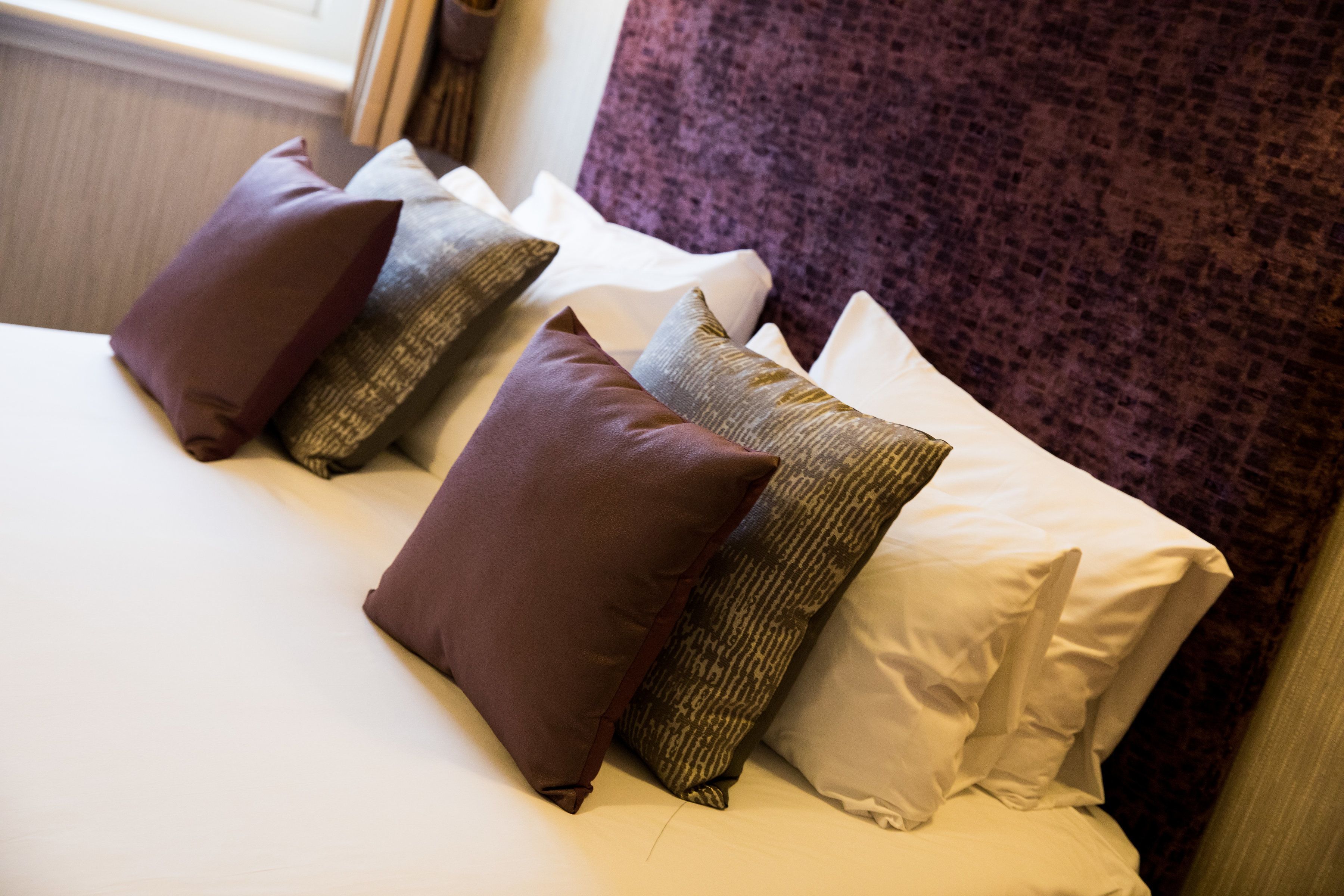 A bed with multiple pillows and a headboard.