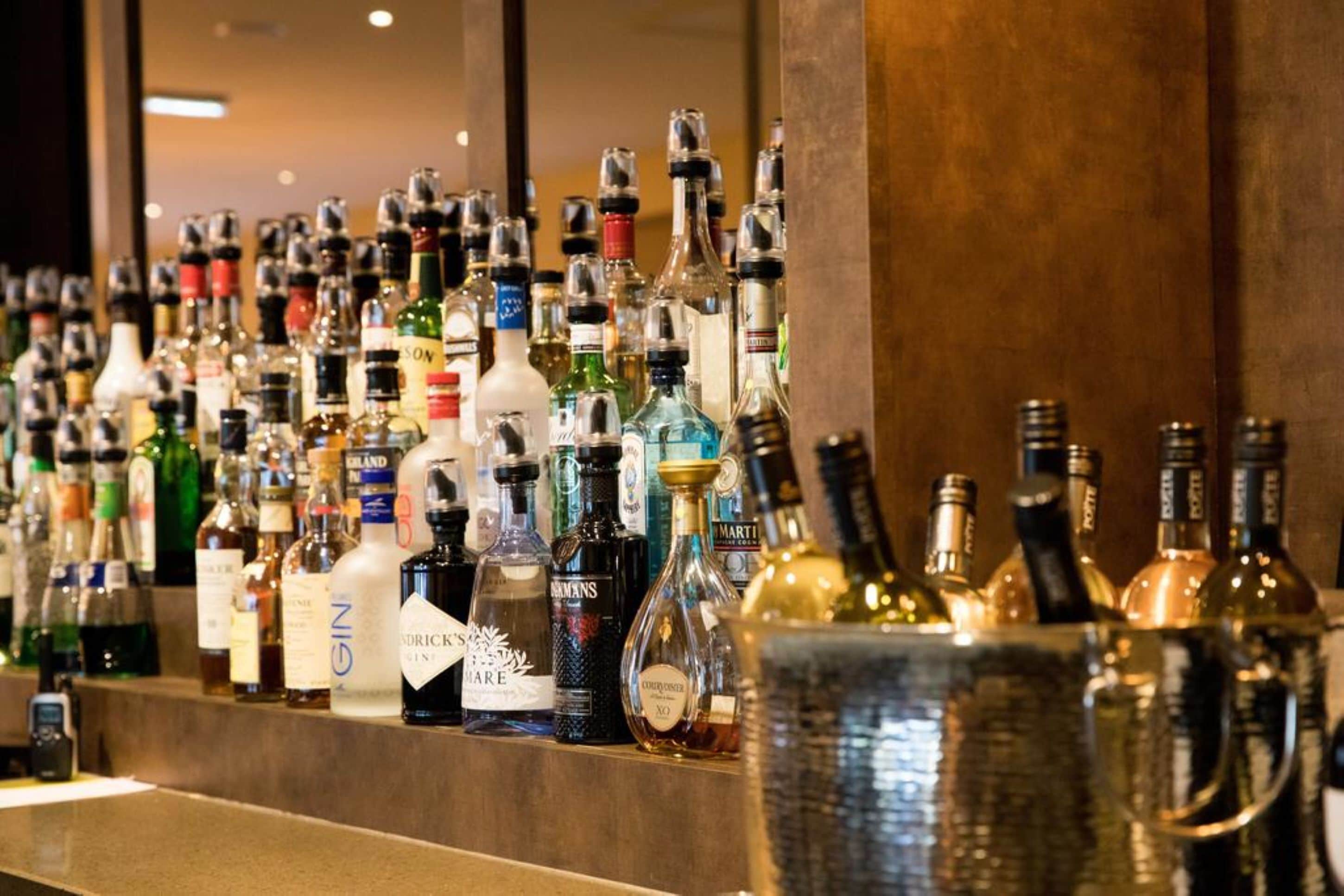 A bar with a variety of liquor bottles and a large metal container.