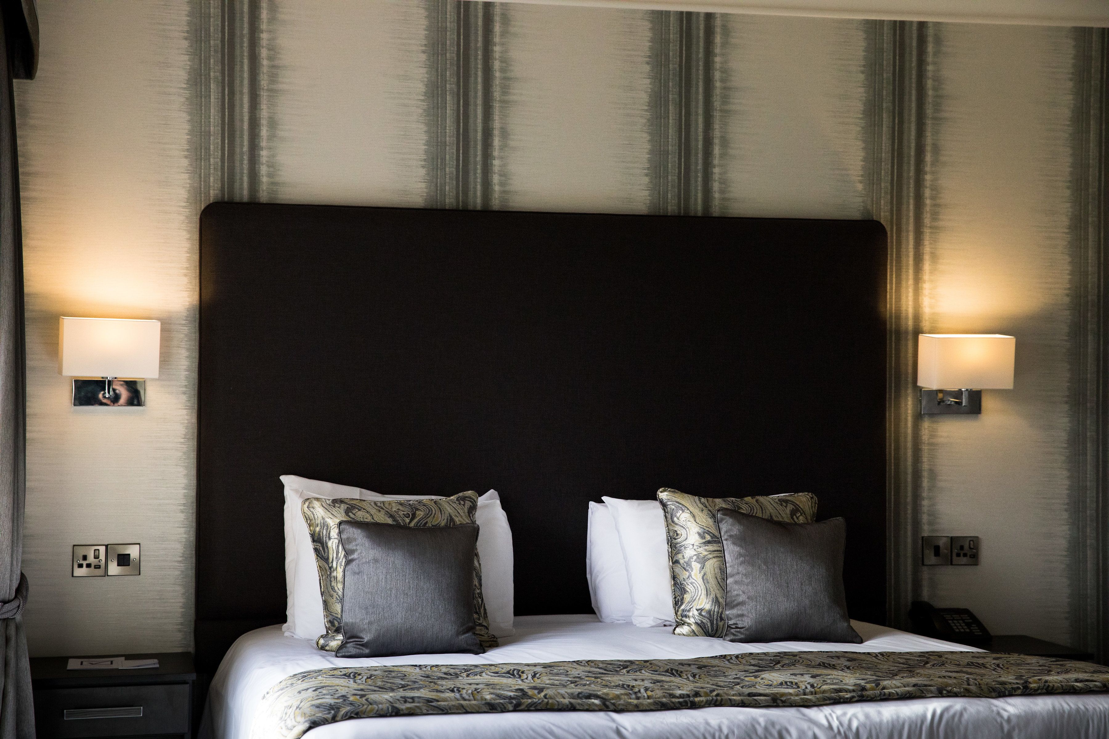 A hotel room with a large bed, two bedside lamps, and a headboard.