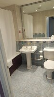 Un baño con lavamanos, inodoro y zona de ducha.