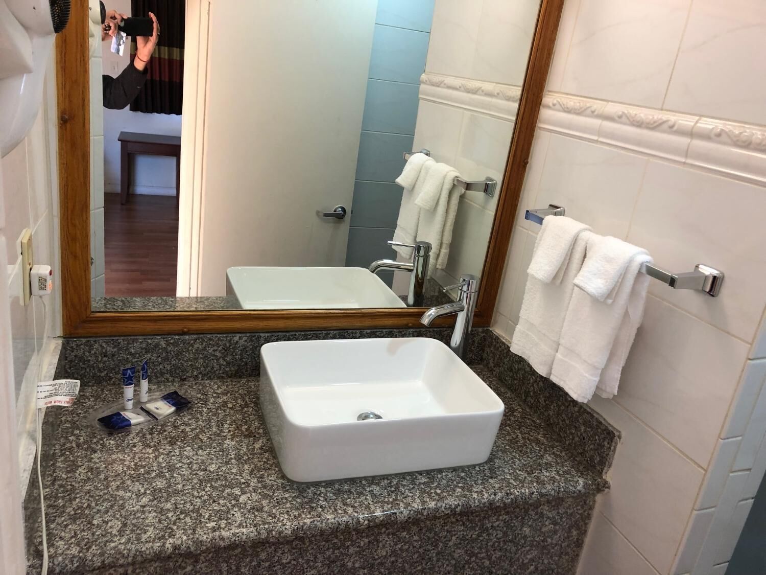 Ein Badezimmer mit einer Granit-Arbeitsplatte, einem weißen Waschbecken, einem Spiegel und einem Handtuchhalter.