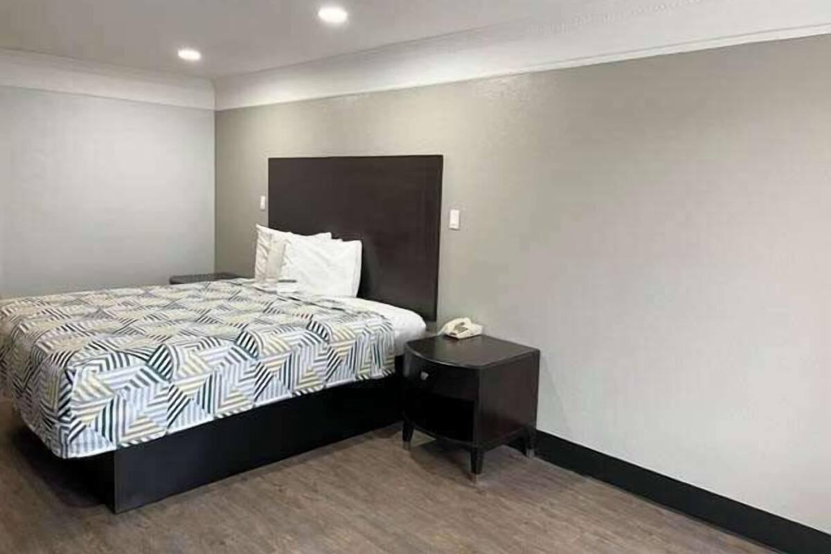 A bedroom with a bed, a nightstand, and a wall-mounted phone.