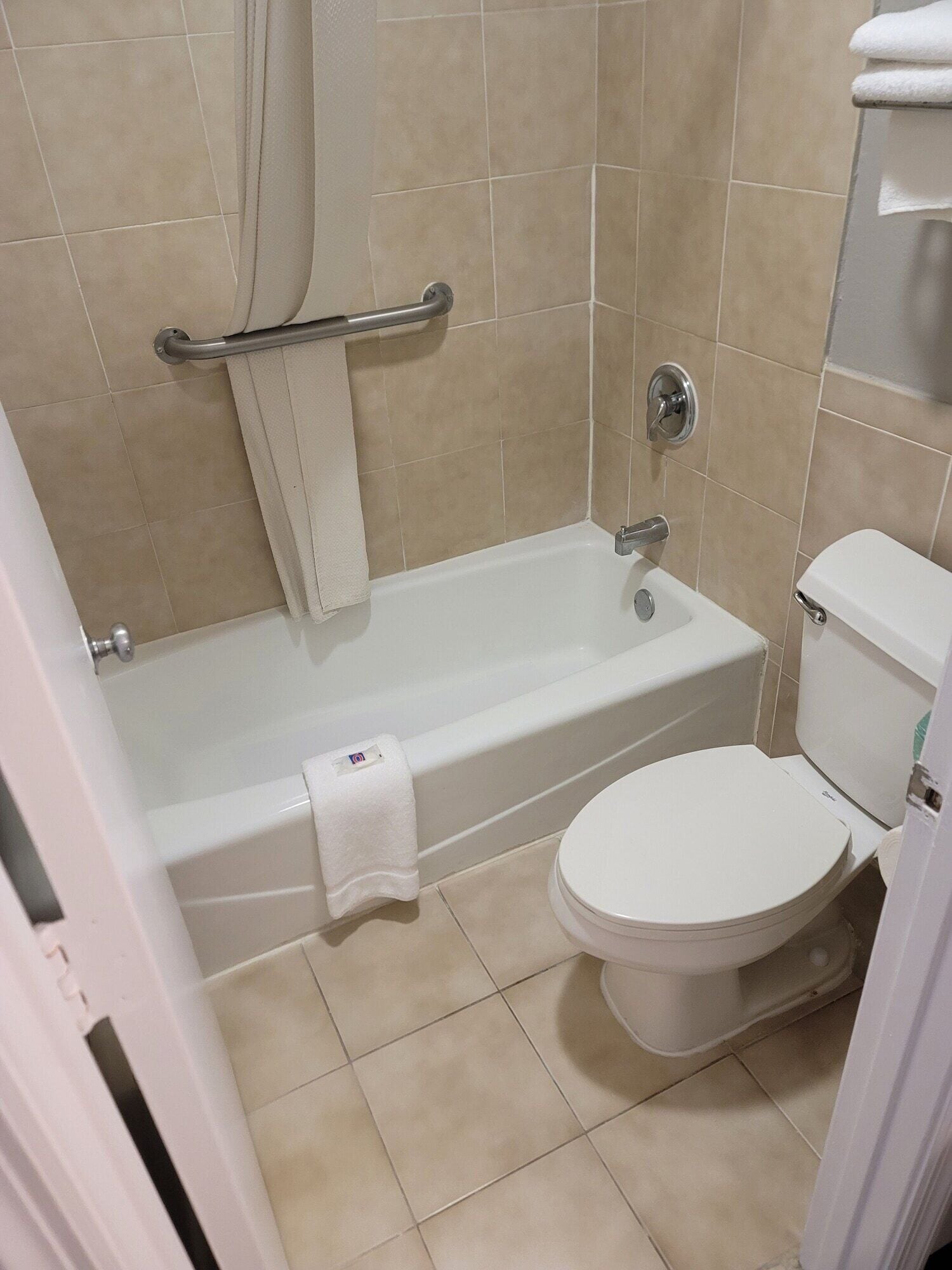 A bathroom with a bathtub, toilet, and a handrail.