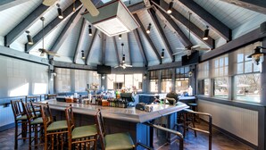 A spacious kitchen with a high ceiling, wooden beams, and a central island with bar stools. - Lanier Islands Resort (Buford)