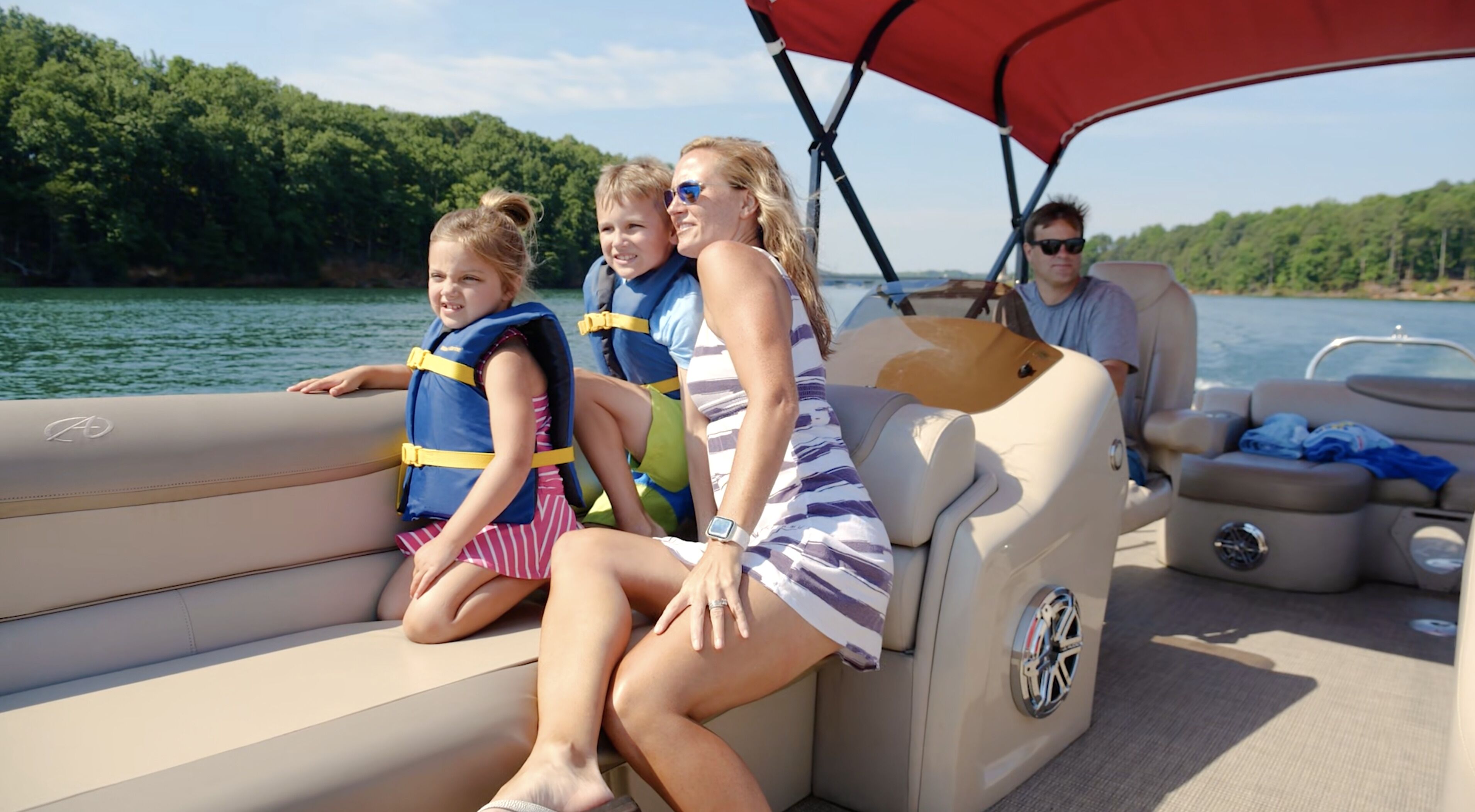 A boat with a seating area, a steering wheel, and a person in the driver's seat.