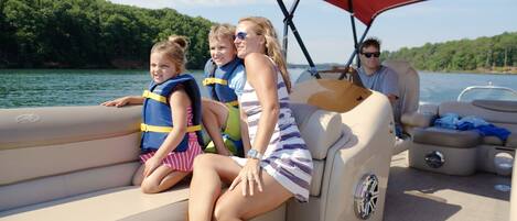A boat with a seating area, a steering wheel, and a person in the driver's seat.
