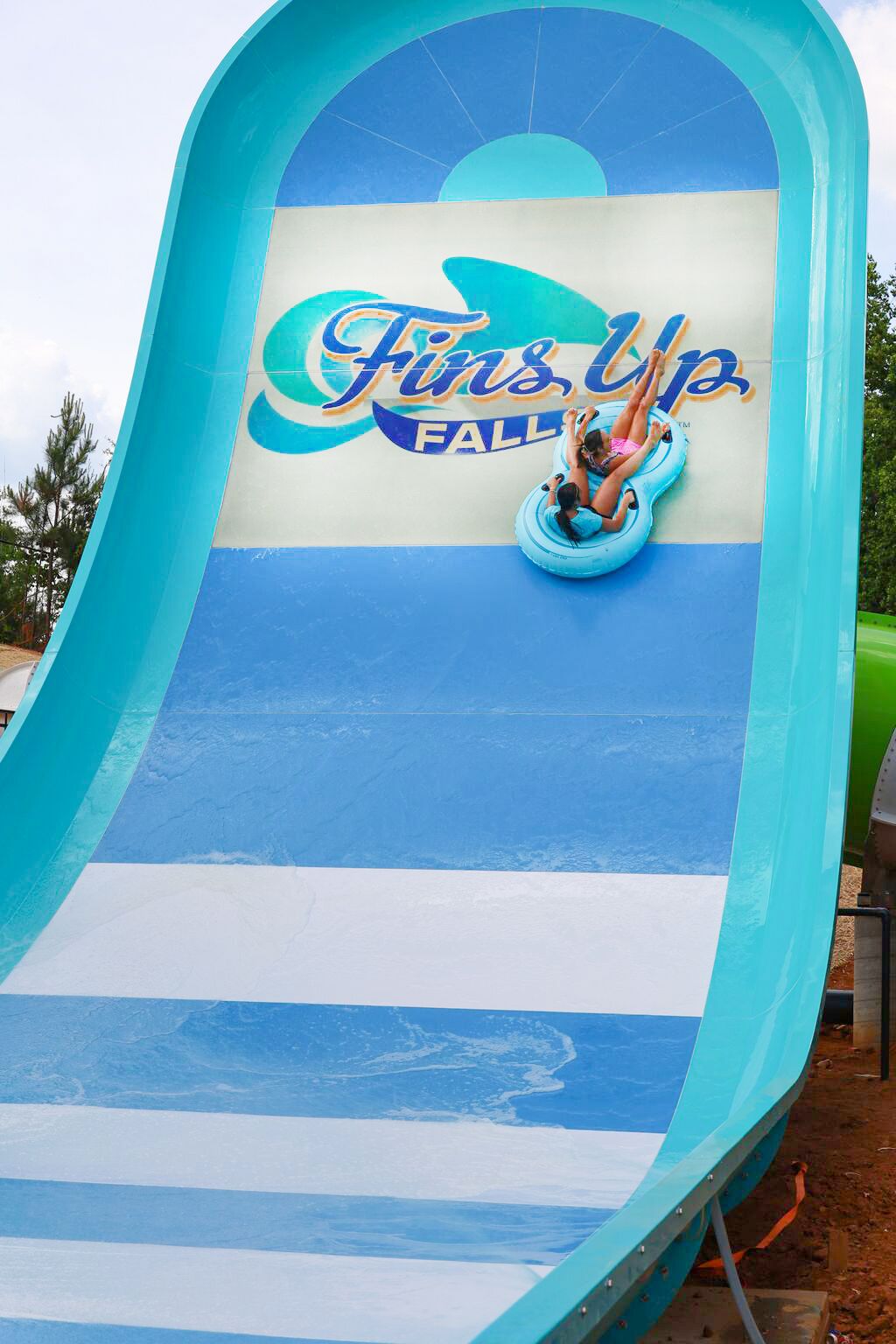 A water slide with the text "Fins Up Fall" and two people sliding down.