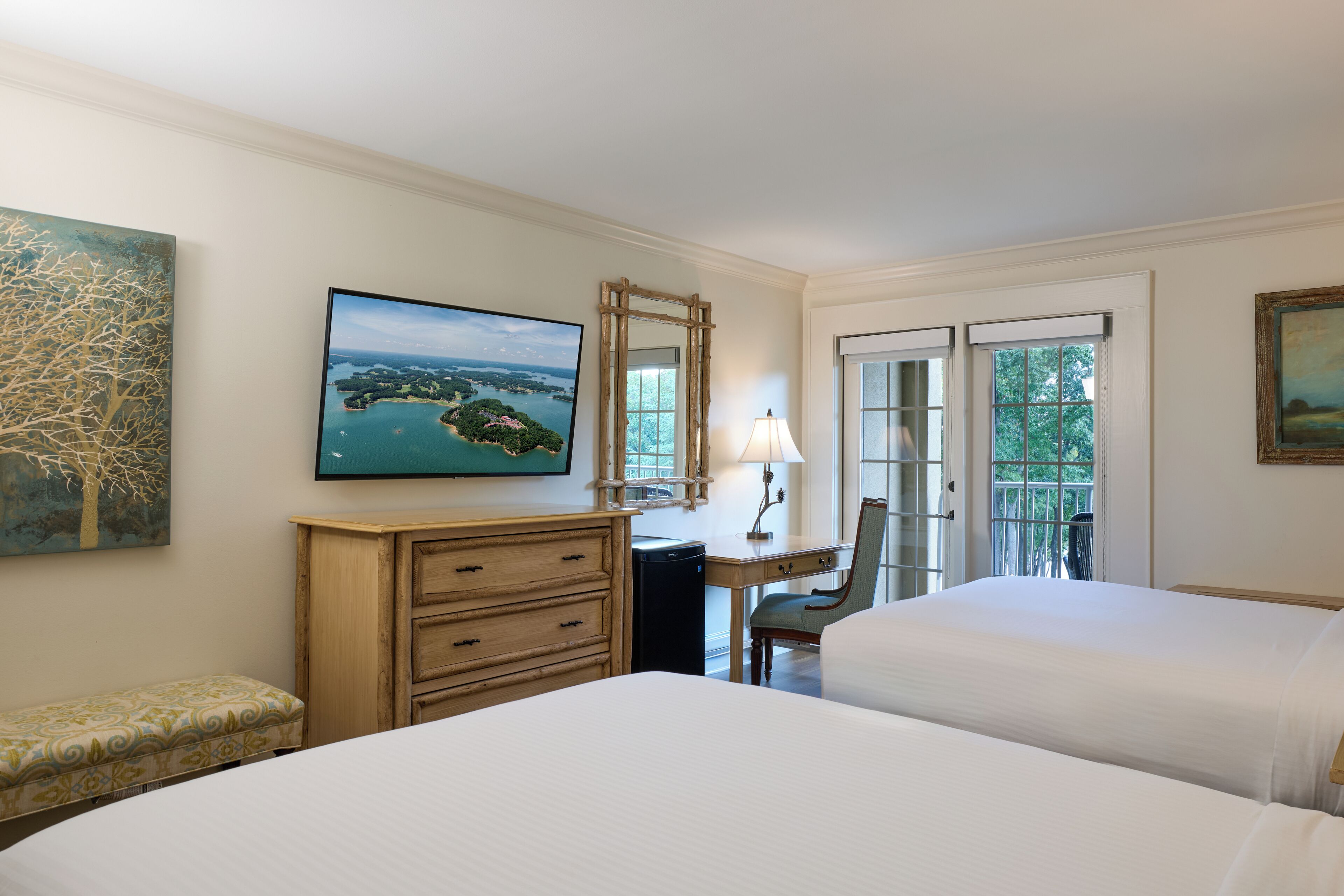 Une chambre d’hôtel avec deux lits, un bureau, une chaise, une commode et une grande fenêtre.