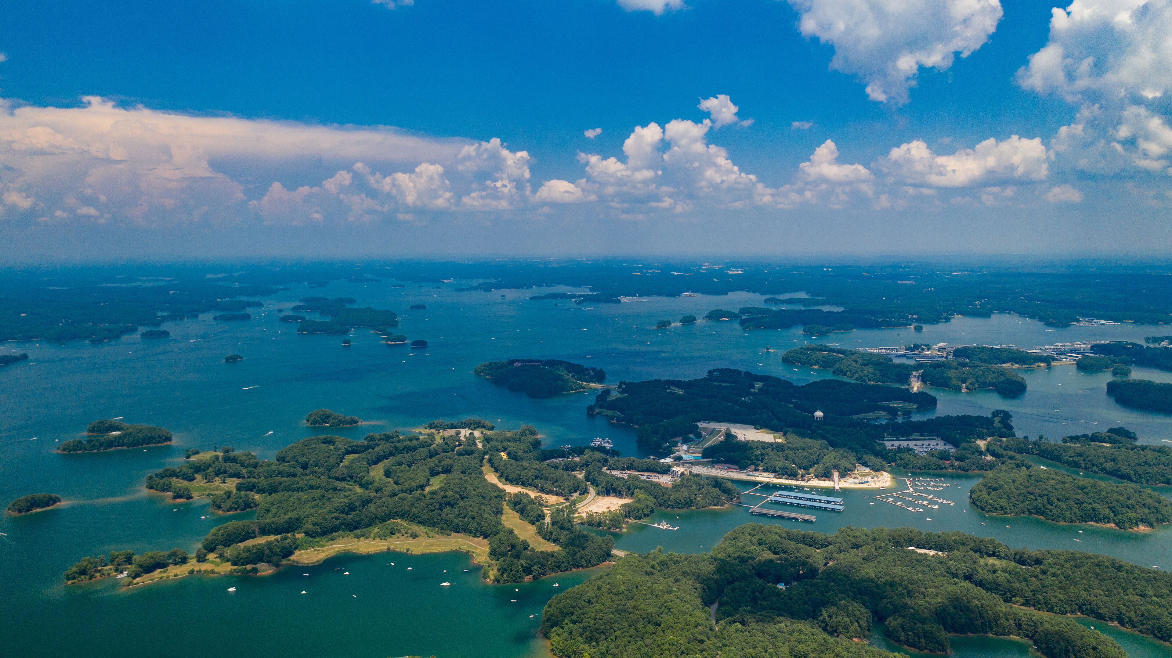 Vista aérea de una zona costera con varias islas, aguas azules cristalinas y embarcaciones dispersas.