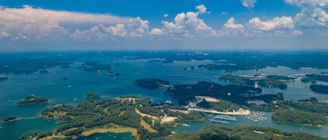 Vista aérea de una zona costera con varias islas, aguas azules cristalinas y embarcaciones dispersas.