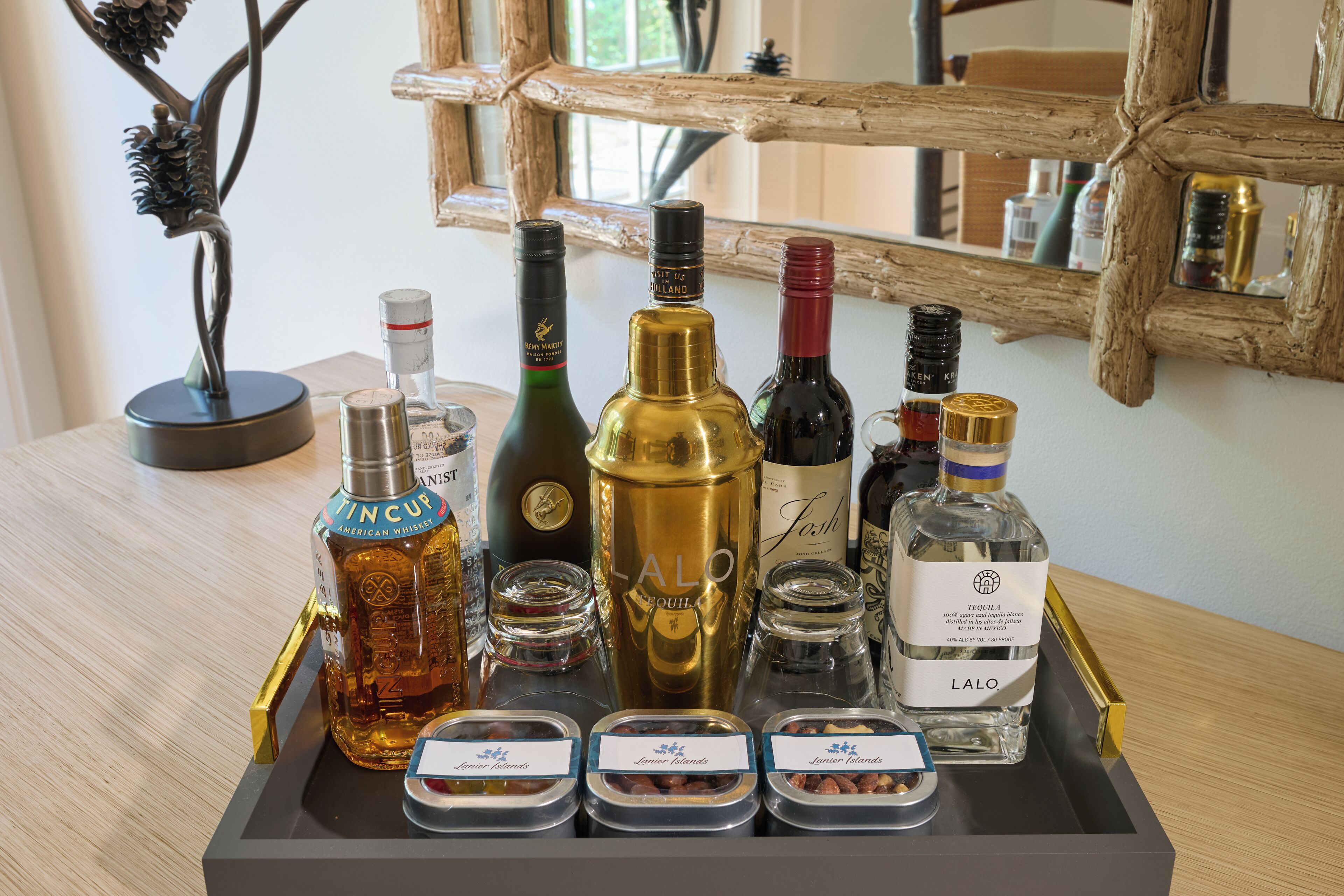 Una bandeja con varias botellas y frascos, incluyendo una botella dorada con la etiqueta "LALO", una botella verde y una botella con tapa roja.