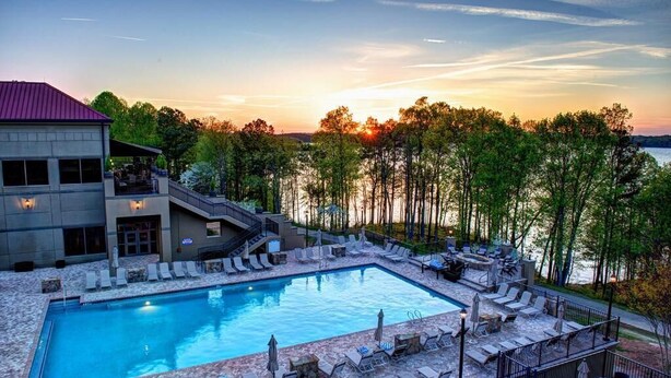 A pool area with lounge chairs and a building with a red roof. - Lanier Islands Resort (Buford)