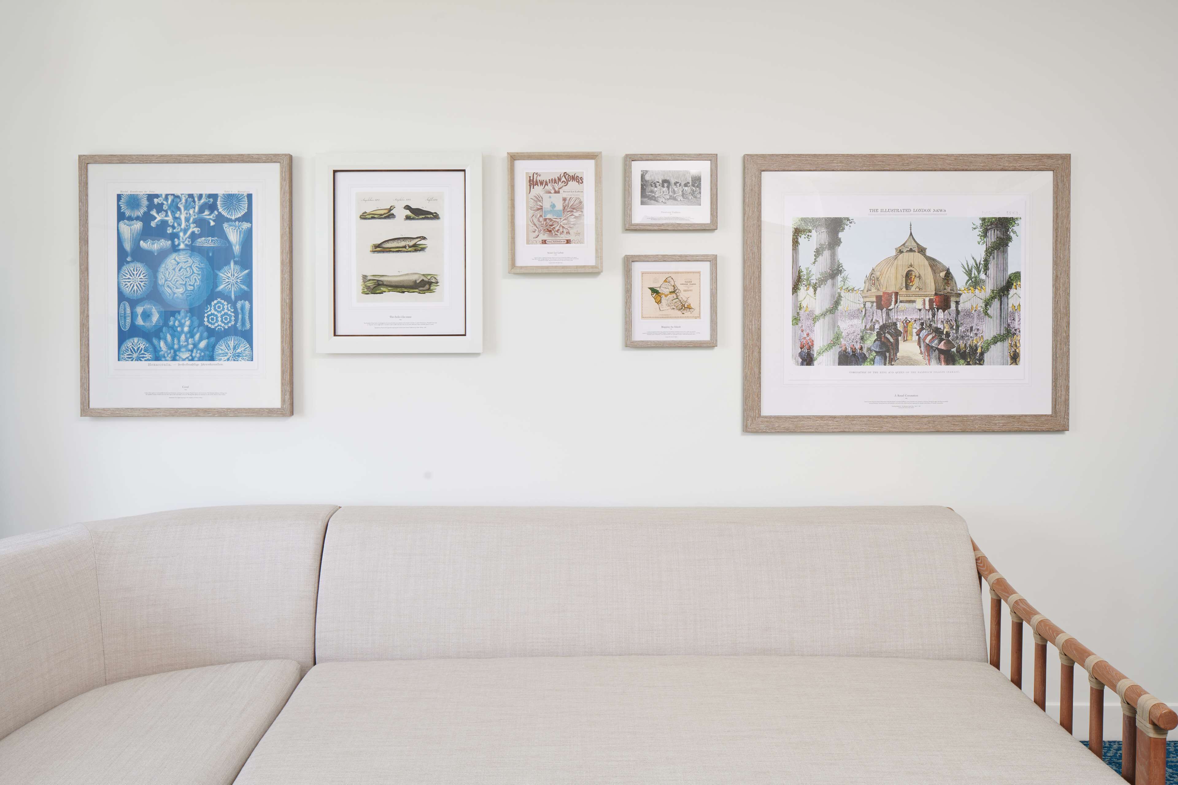 A wall with framed artworks and a sofa.