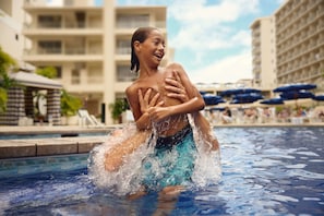 A swimming pool with a person in the water, surrounded by buildings and umbrellas. - OUTRIGGER Reef Waikiki Beach Resort (Honolulu)
