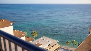 Une vue sur la côte, avec un bâtiment donnant sur la mer, agrémenté de balcons et de palmiers.