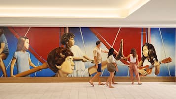 Ein Wandgemälde zeigt Personen in unterschiedlichen Posen, ein Fliesenboden und eine weiße Decke.