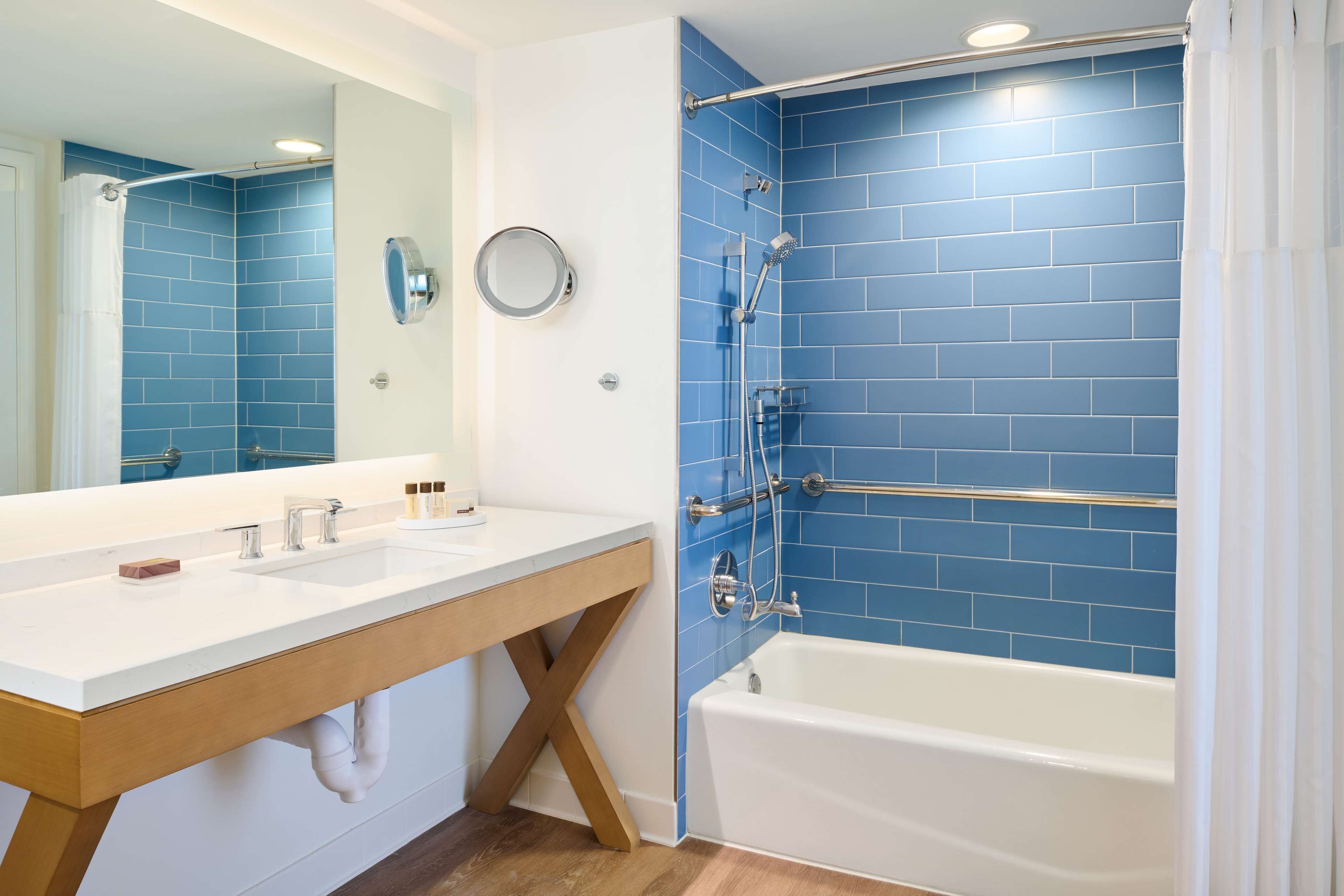 A bathroom with a white sink, a bathtub, and blue-tiled walls.