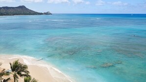 Una playa con agua turquesa cristalina, una orilla arenosa y una montaña al fondo.