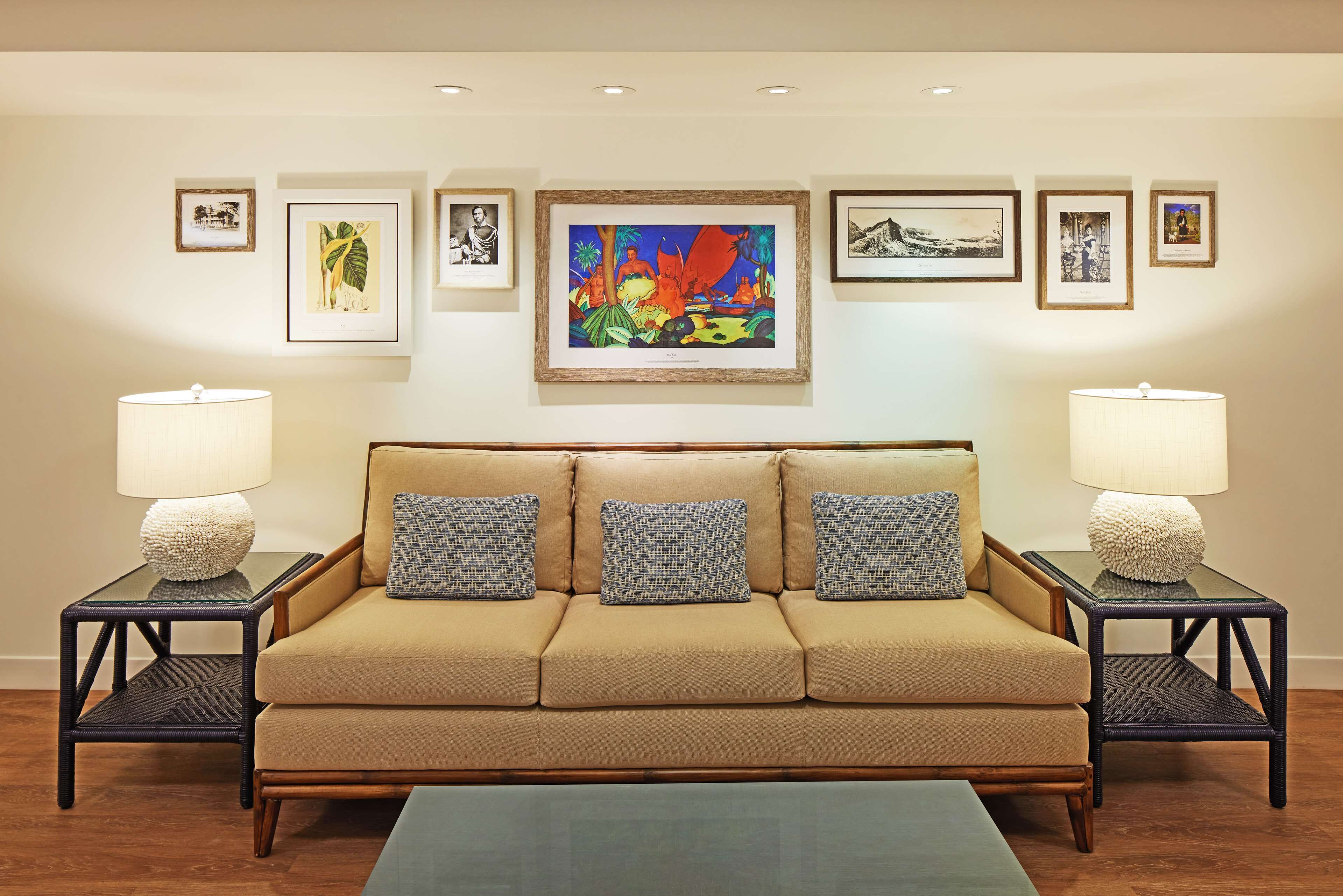 A living room with a beige sofa, patterned pillows, two side tables with lamps, and framed artwork on the wall.