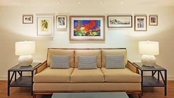 A living room with a beige sofa, patterned pillows, two side tables with lamps, and framed artwork on the wall.