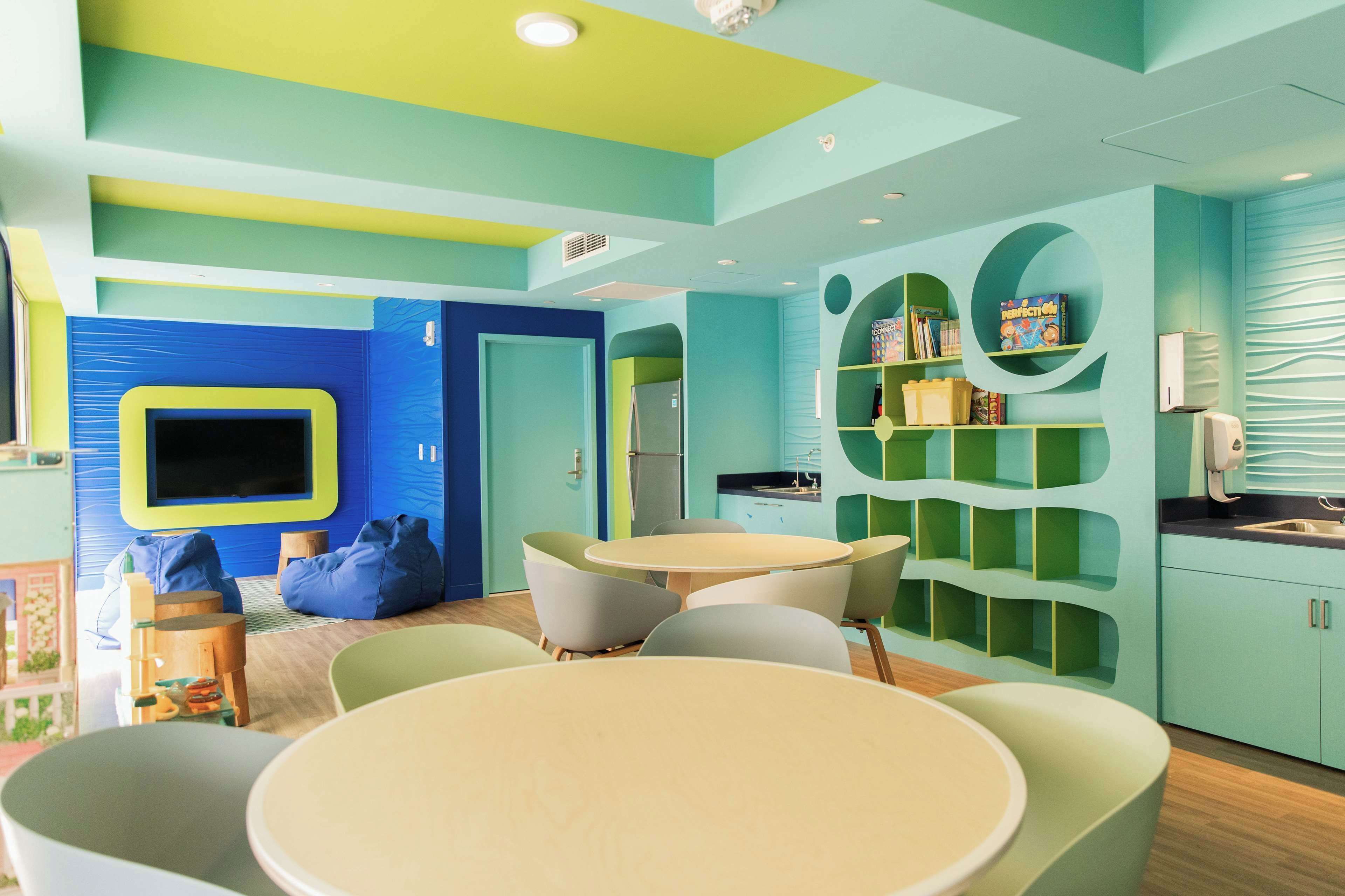 A children's playroom with a TV, seating, and shelves with toys.