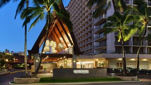 Un hotel con fachada moderna, palmeras y una entrada bien iluminada.