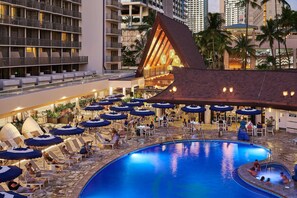 A hotel with a pool area, lounge chairs, umbrellas, and a distinctive building with a sloped roof. - OUTRIGGER Reef Waikiki Beach Resort (Honolulu)