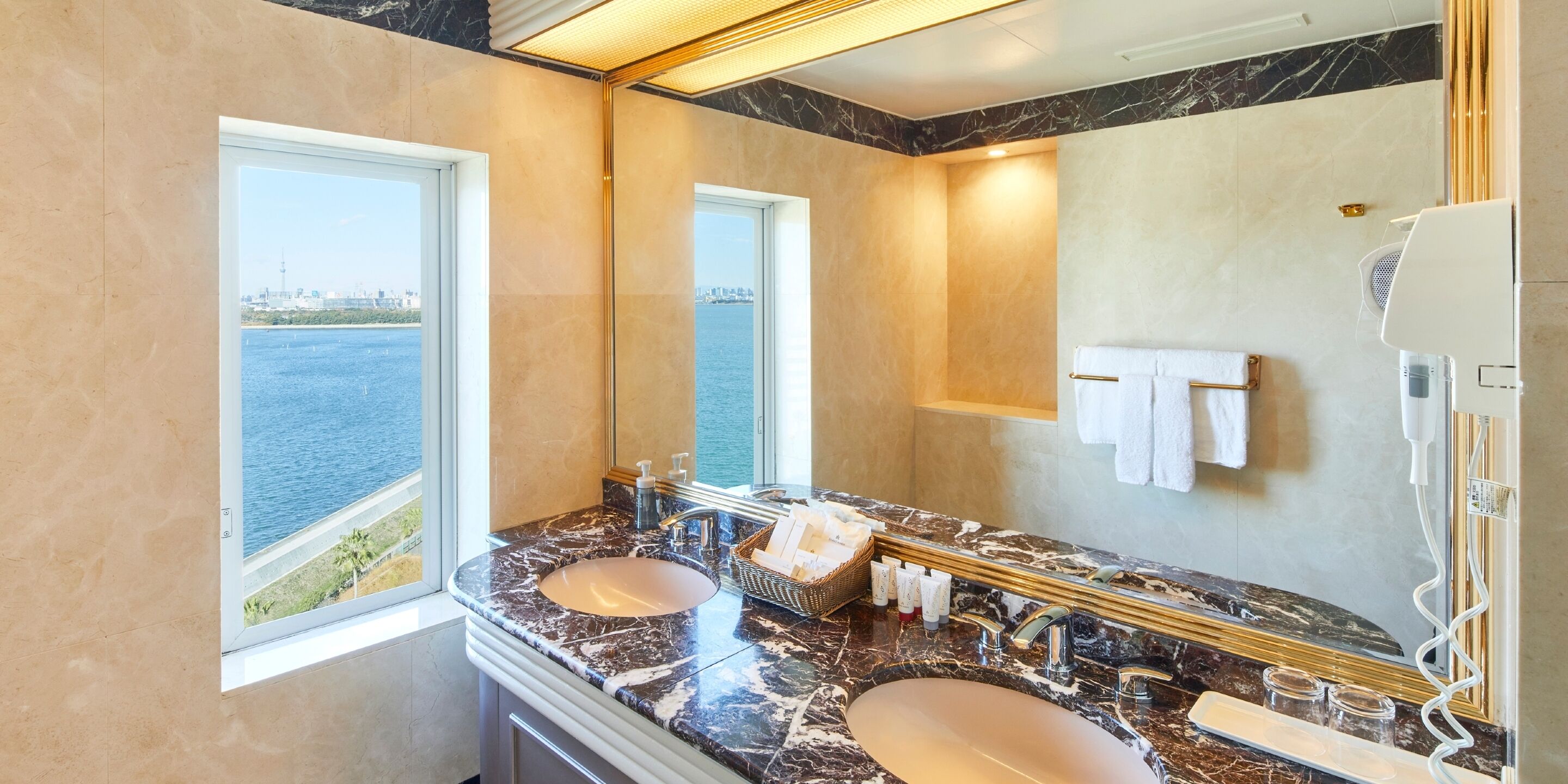 A bathroom with two sinks, a large mirror, and a view of the water.