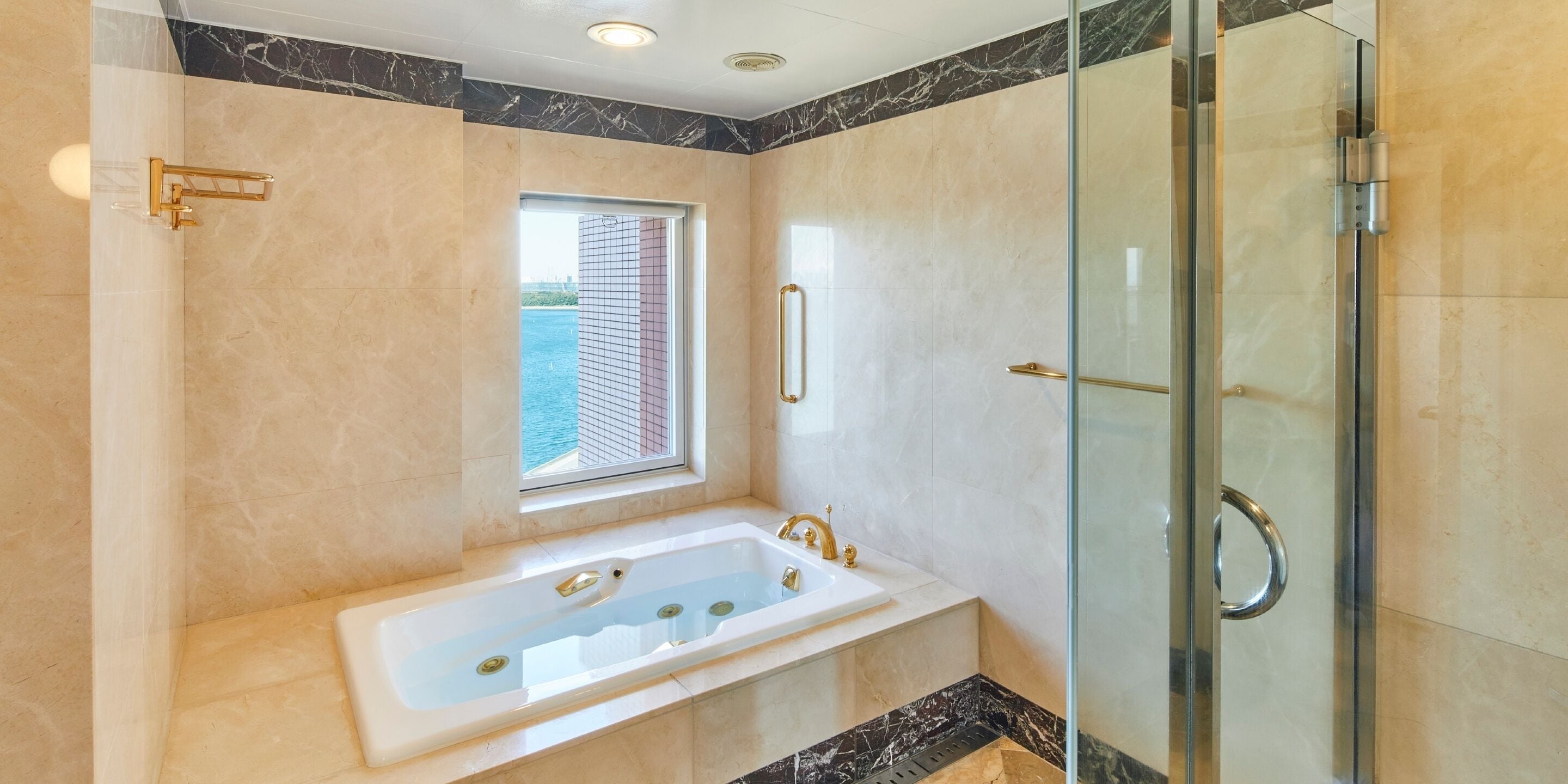 A modern bathroom with a large bathtub, a glass shower enclosure, and a window providing a view of the outside.