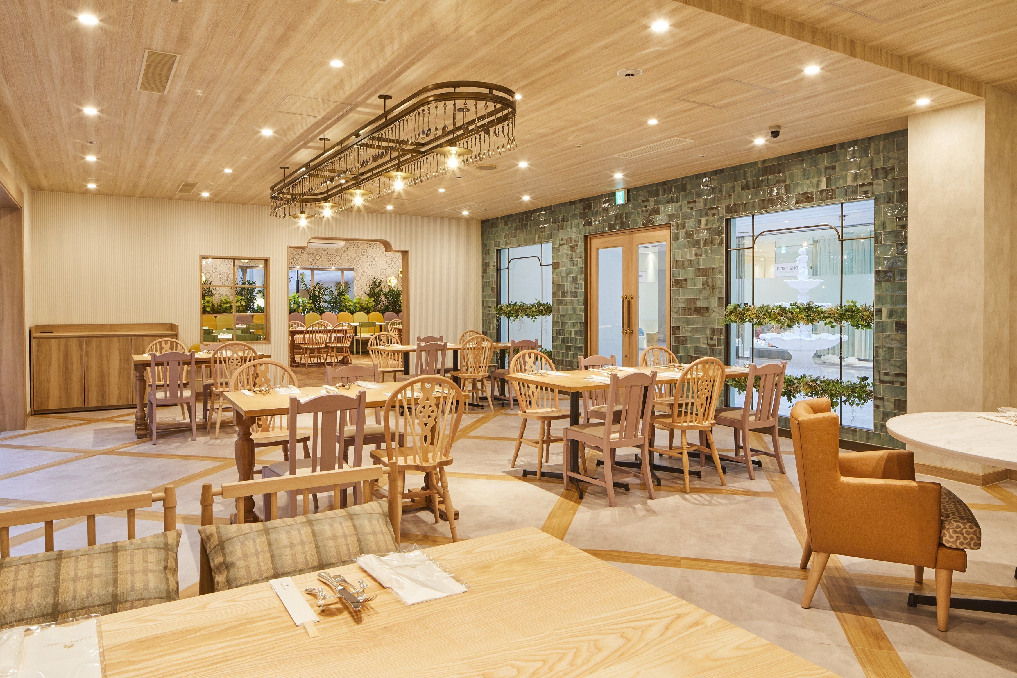 A spacious dining area with wooden furniture and a modern chandelier.