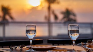 A table set for dining with three glasses of water, cutlery, and salt and pepper shakers, overlooking a body of water during sunset. - Grand Nikko Tokyo Bay Maihama (Urayasu)