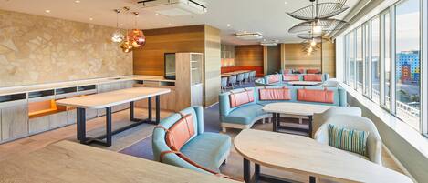 A modern restaurant with a stone wall, wooden paneling, and large windows offering a city view.