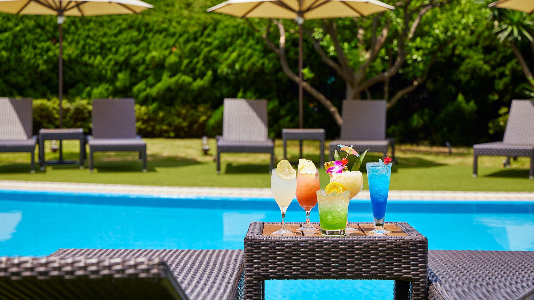 A poolside area with lounge chairs and a table with colorful drinks.