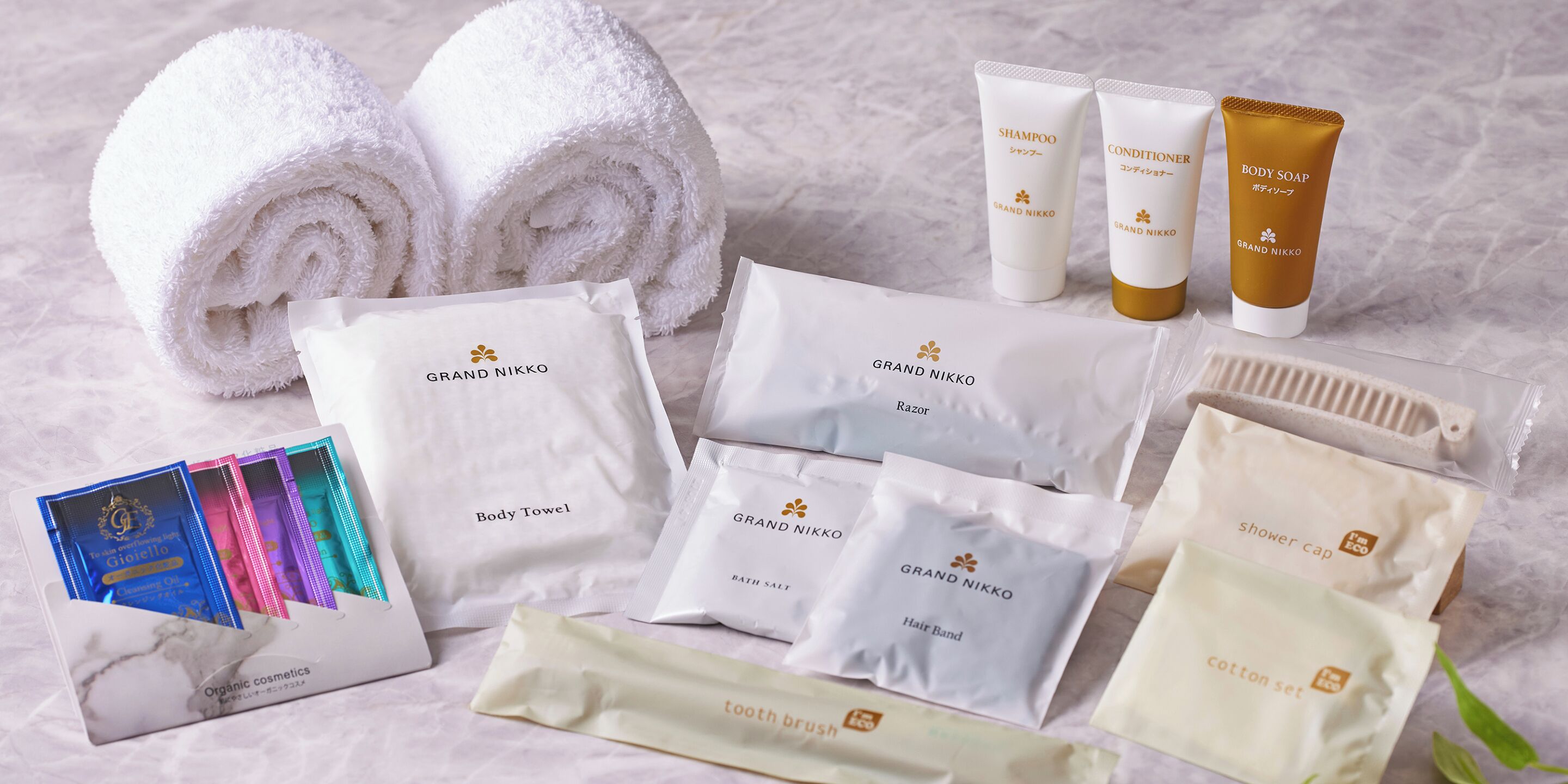 Une gamme de produits de toilette comprenant des serviettes, du shampoing, de l’après-shampoing, du savon, des rasoirs, des élastiques à cheveux, des cotons-tiges et une brosse à dents.