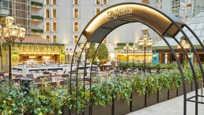 An indoor dining area with a central table surrounded by chairs, a decorative archway with the name 'Le Jardin', and greenery along the walls. - Grand Nikko Tokyo Bay Maihama (Urayasu)