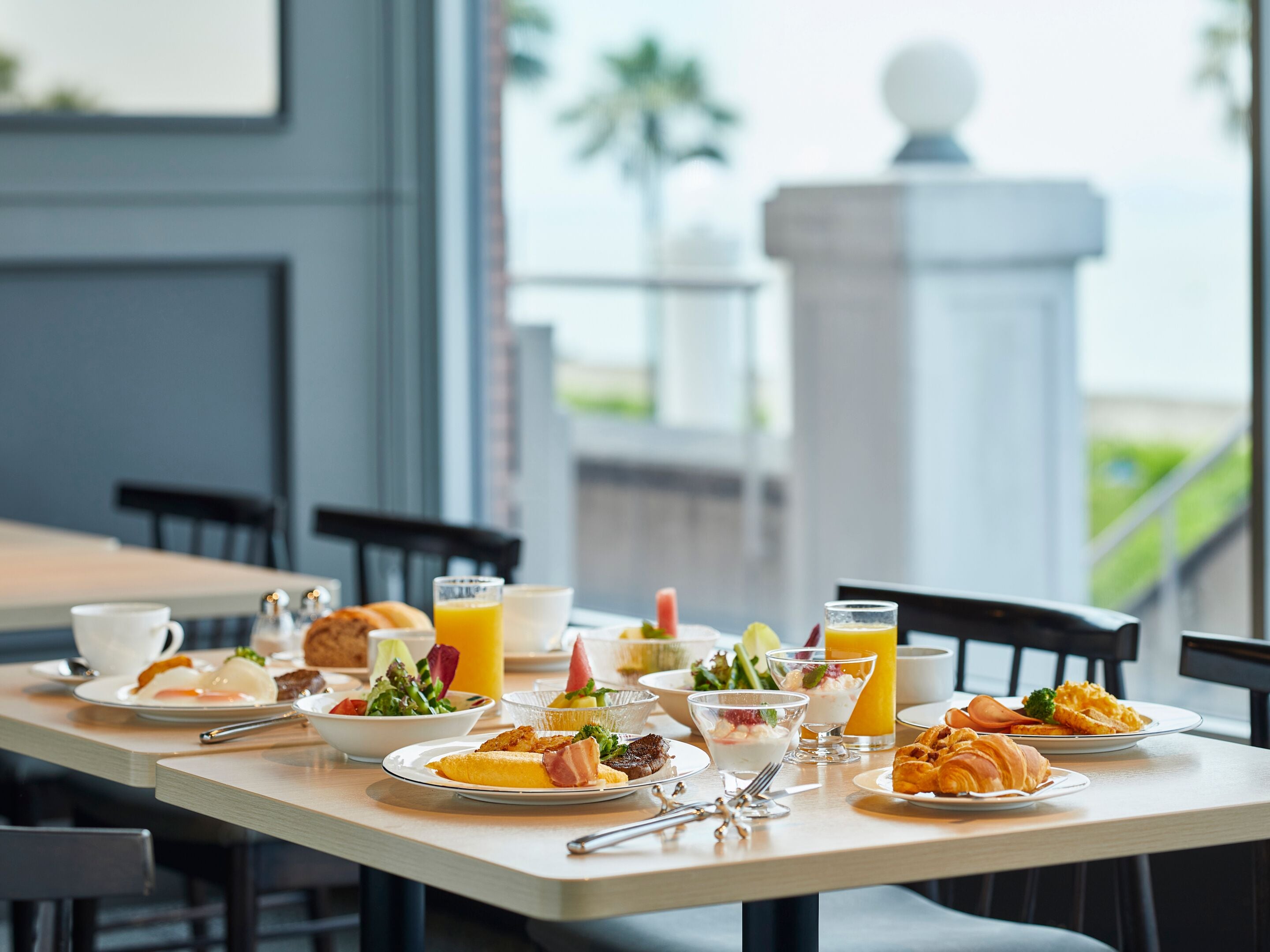 A breakfast table set with plates of food, drinks, and cutlery.