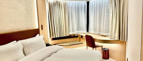 A modern hotel room with a large bed, a desk, and a chair.