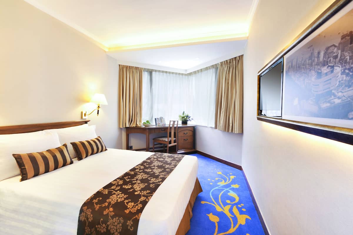 A hotel room with a large bed, a desk, and a television.