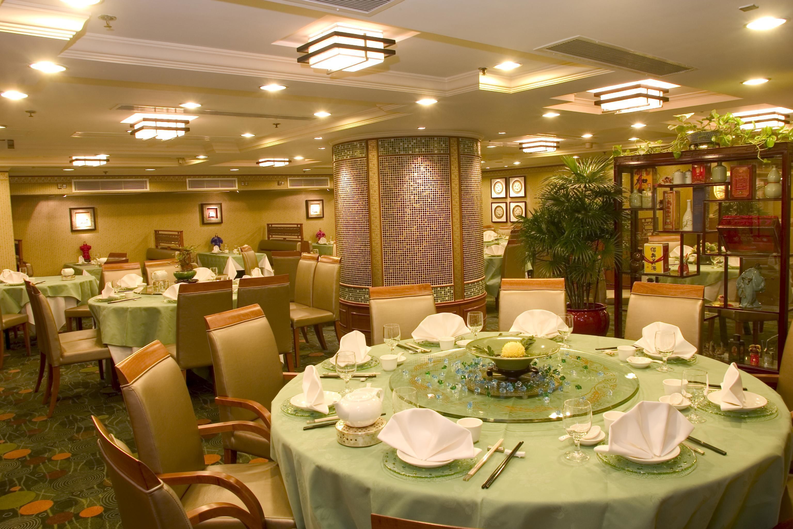 A hotel dining area with round tables, chairs, and a central decorative column.