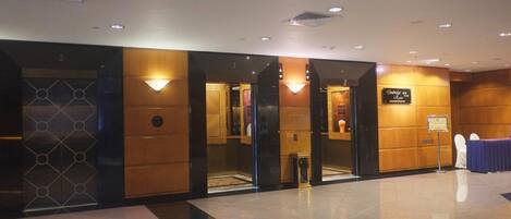 A hotel lobby with a reception desk, elevators, and a sign indicating the name of the hotel.