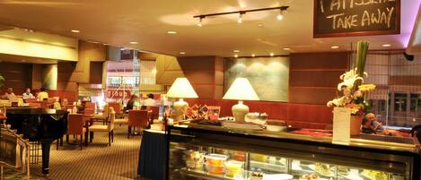 Vestíbulo de hotel con zona de buffet, asientos y un piano.