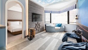 A modern bedroom with a bed, a seating area, and a TV. - The Kimberley Hotel (Kowloon)