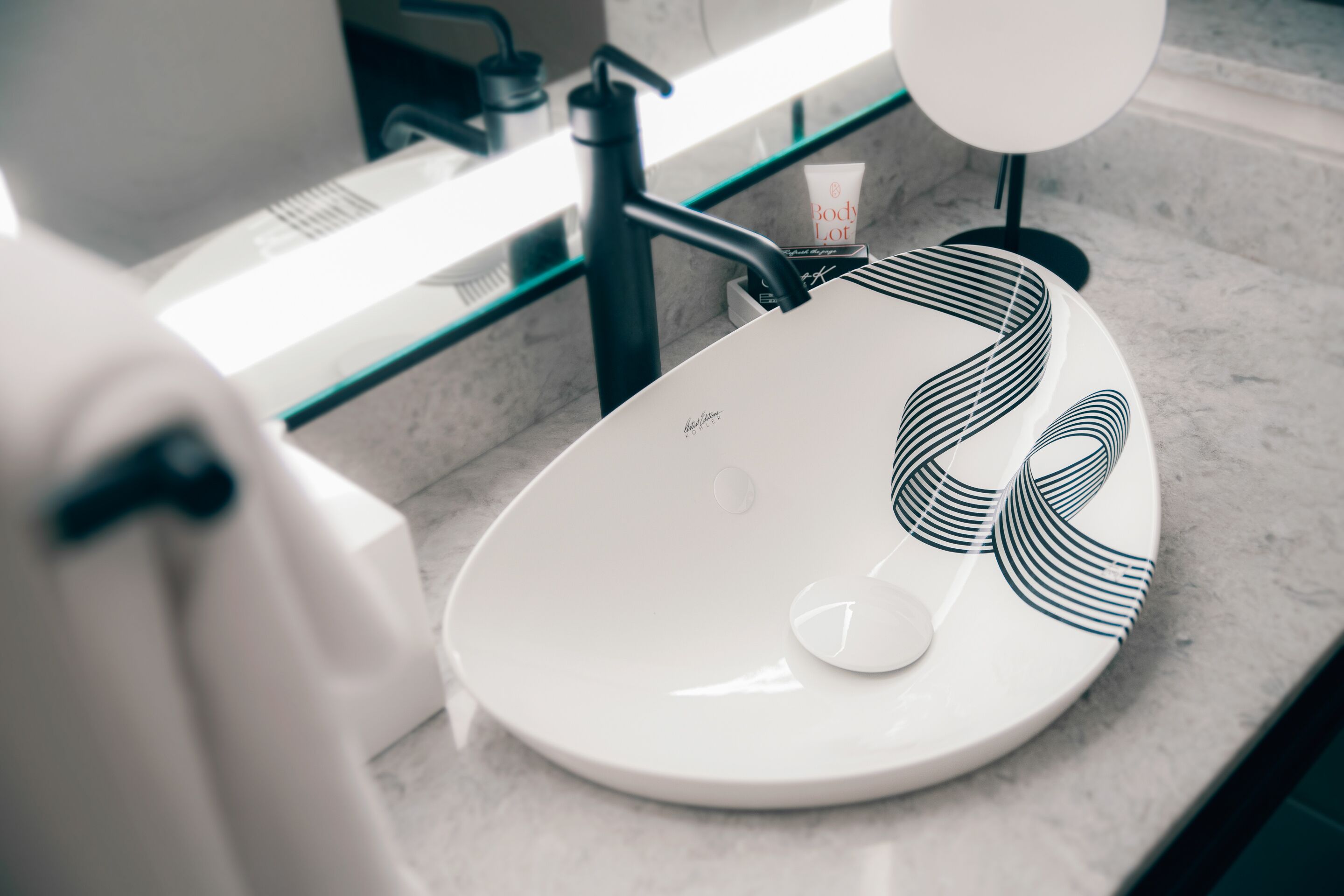 A bathroom sink with a modern design, a soap dispenser, and a mirror.